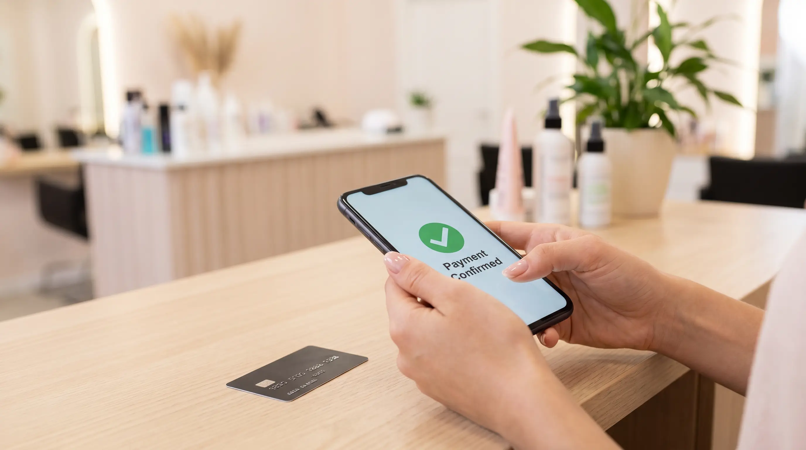 Maos a segurar smartphone com confirmacao de pagamento antecipado no salao